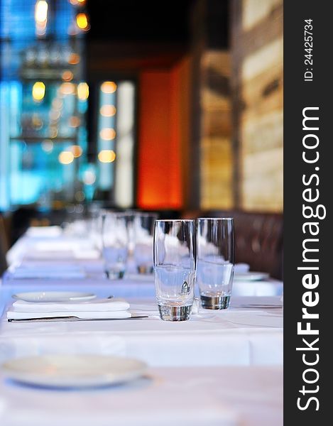 Glasses sit perfectly in line with their place settings on perfectly white tablecloths. Glasses sit perfectly in line with their place settings on perfectly white tablecloths.