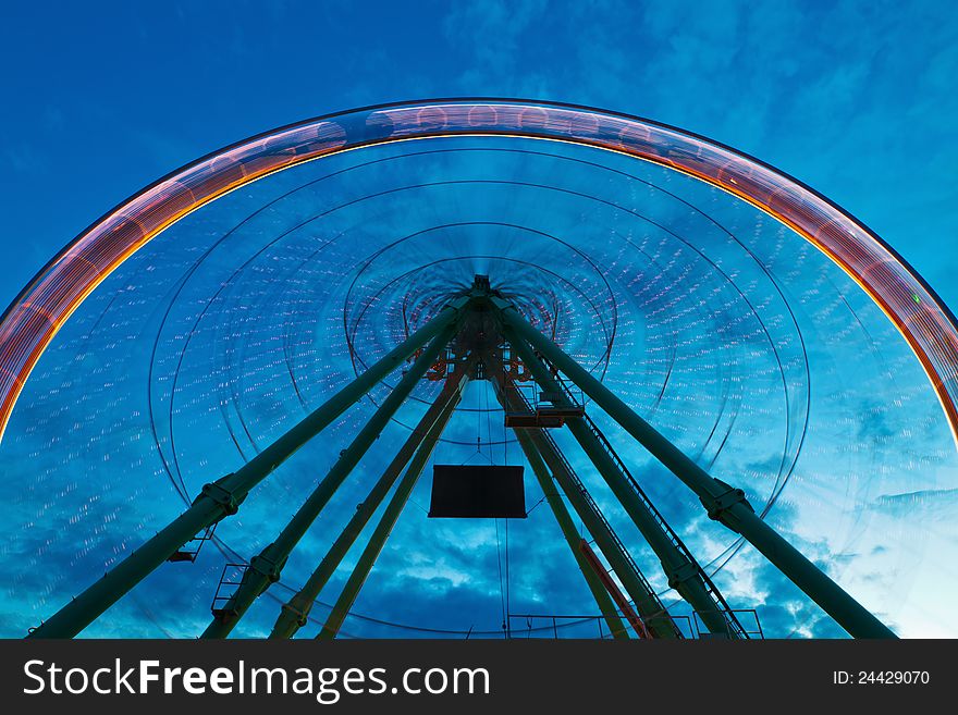 Ferris wheel in motion blur against a blue night sky