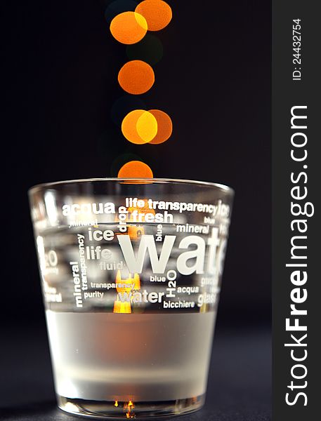 Glass of water on a black background with lights