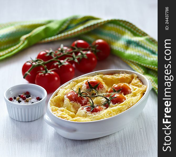 Tomato gratin with cheese and zucchini in baking dish