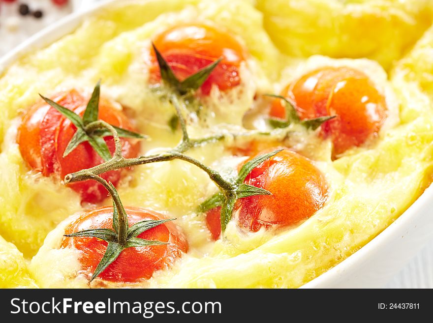 Tomato gratin with cheese and zucchini in baking dish