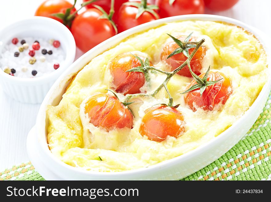 Tomato gratin with cheese and zucchini in baking dish