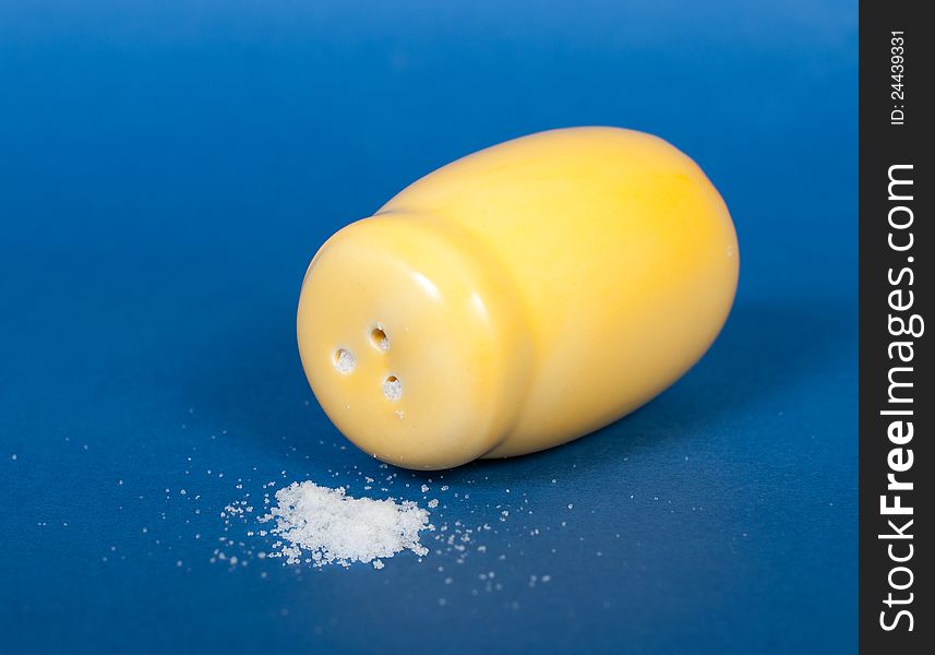 Yellow ceramic salt shaker on a blue background