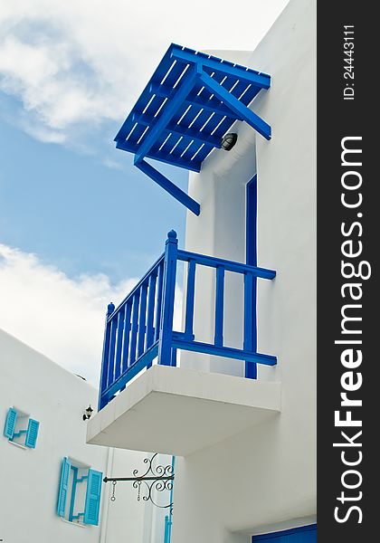 Blue balcony of white house and cloudy sky