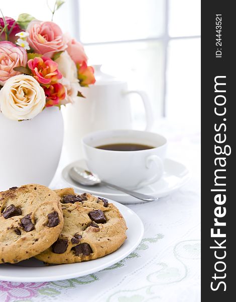 Chocolate chip cookie  on white plate with black coffee and flower. Chocolate chip cookie  on white plate with black coffee and flower