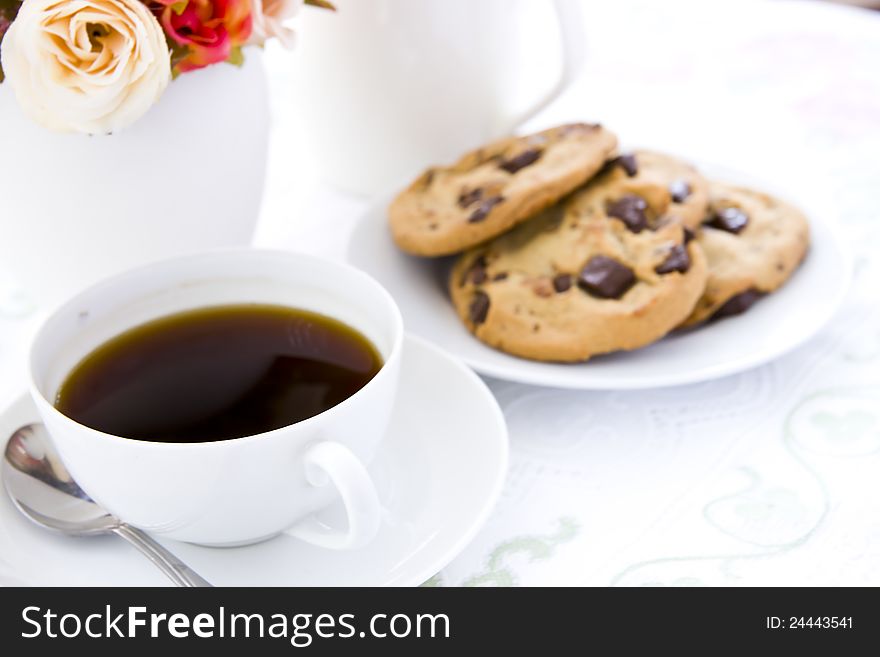 Chocolate chip cookie  on white plate with black coffee and flower. Chocolate chip cookie  on white plate with black coffee and flower