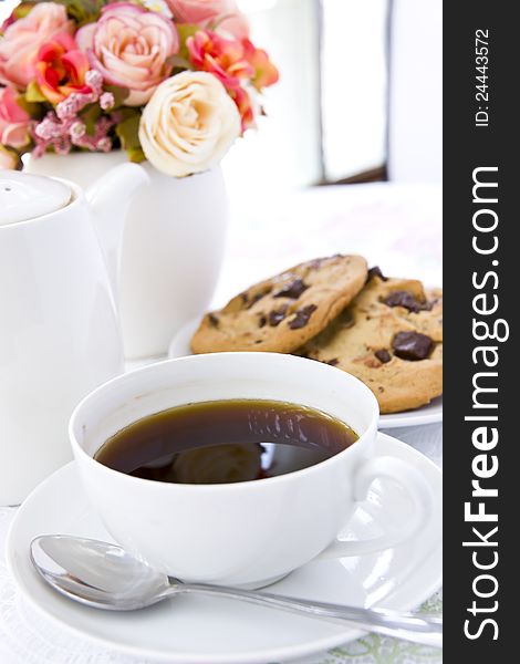 Chocolate chip cookie on white plate with black coffee and flower. Chocolate chip cookie on white plate with black coffee and flower