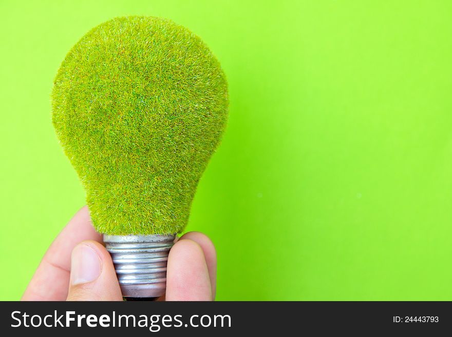 Light blub in hand with green background, eco energy concept