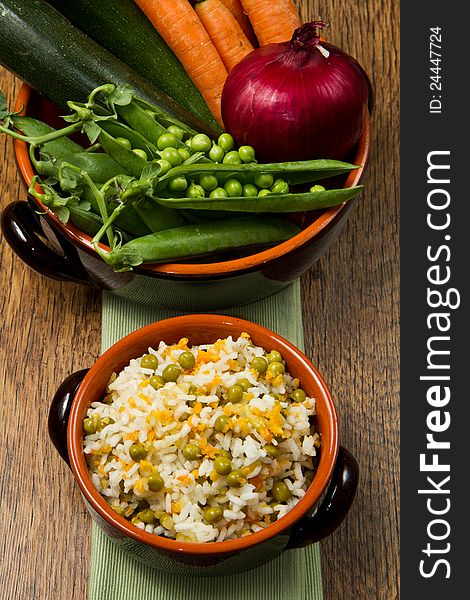 Risotto with fresh vegetables in crock on wooden table