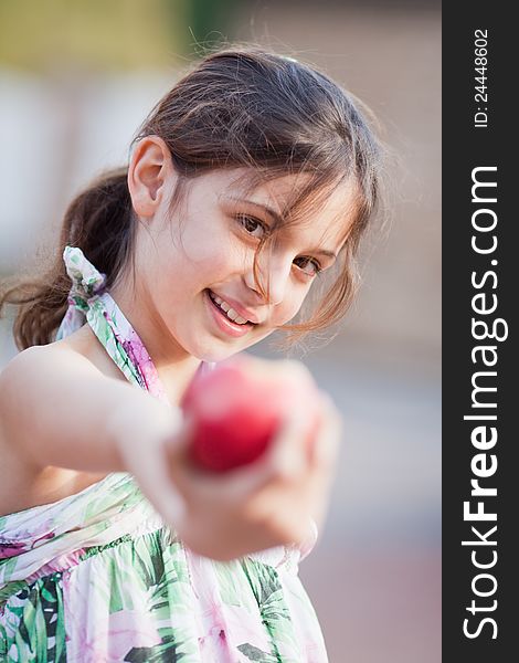 Pretty young girl smiles and reaches a red apple. Pretty young girl smiles and reaches a red apple