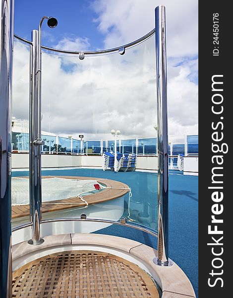 On sundeck of the cruise ship: deck chairs, shower, and pool on sunny day. On sundeck of the cruise ship: deck chairs, shower, and pool on sunny day