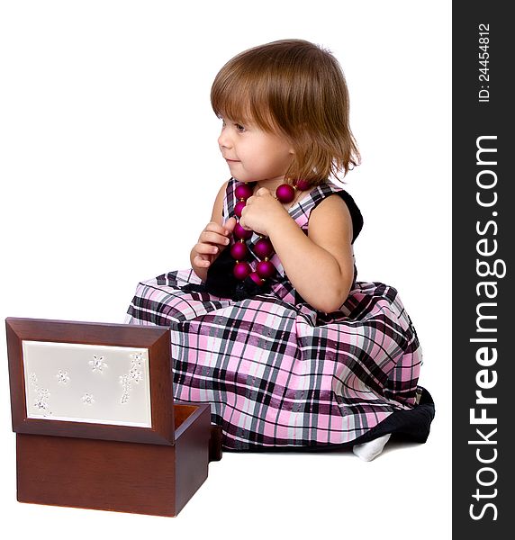 The little girl opens a box with a beads. Isolated on a white background