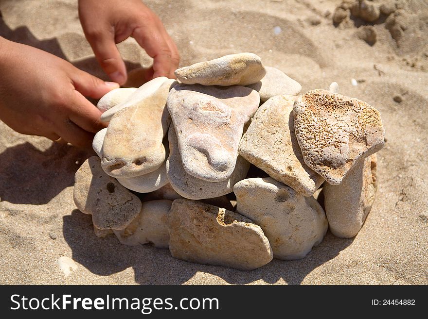 Man's hands put stones on sand