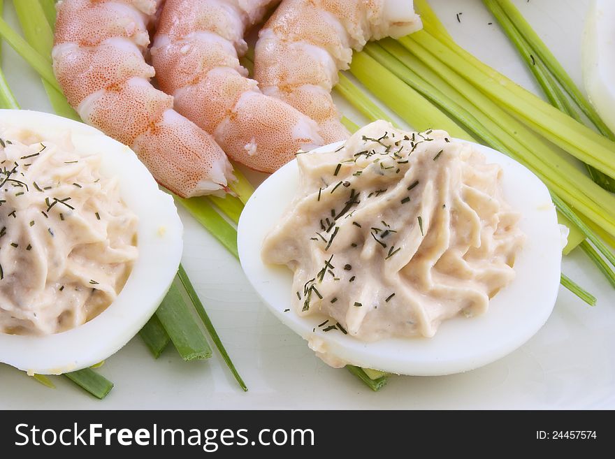 Deviled eggs with salmon cream, sprinkled with dill and decorated with prawns and leeks