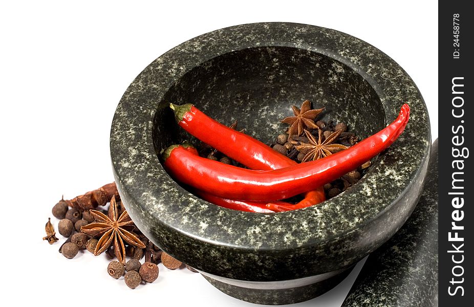 Stone mortar with spices and chilli on a white background