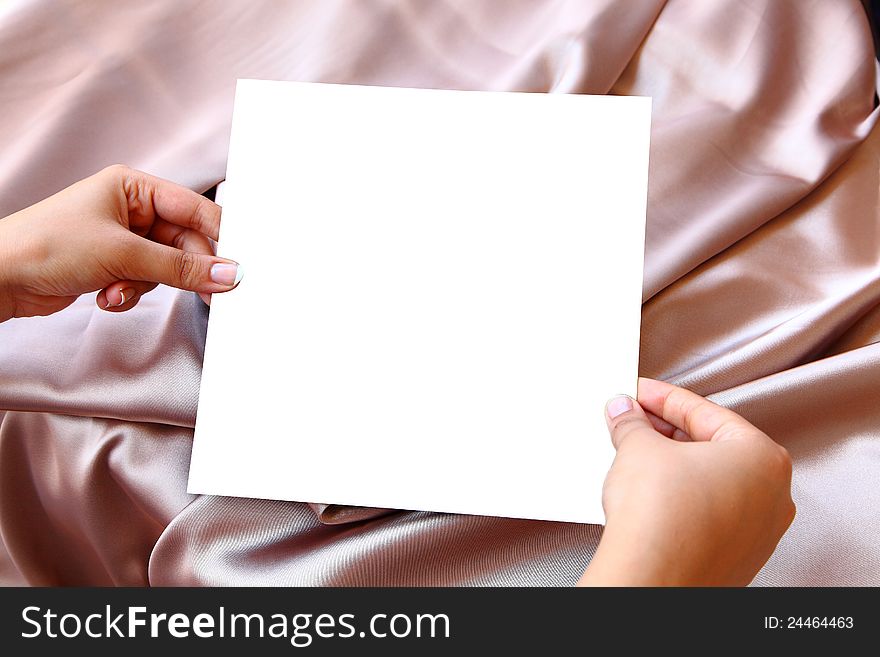 Women Hands Holding Blank white paper on pink Satin background