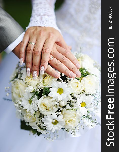 Hands and rings on wedding bouquet. Hands and rings on wedding bouquet