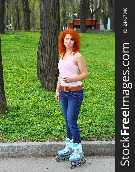 Ginger girl on roller skates listening to music in the park