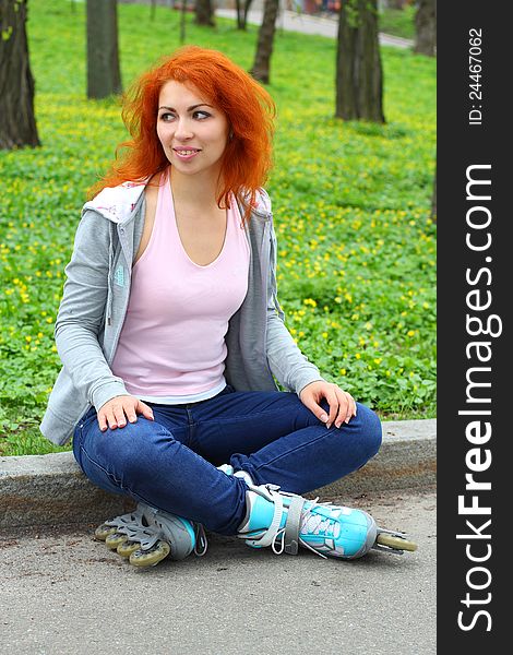 Relaxing ginger girl on skates in the park looking away