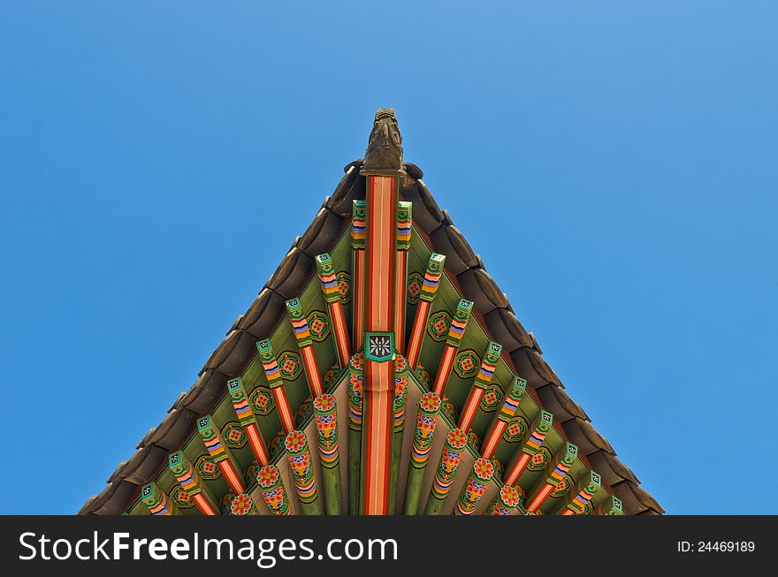 Ancient korean style end roof structural decorative ornament in blue sky. Ancient korean style end roof structural decorative ornament in blue sky