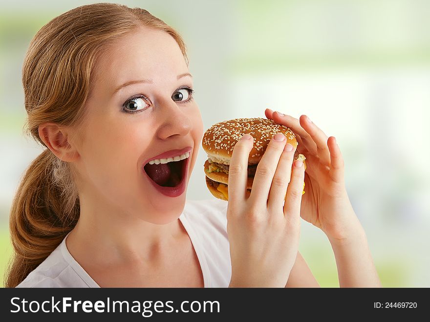 Attractive young woman eats unhealthy food, hamburger. Attractive young woman eats unhealthy food, hamburger