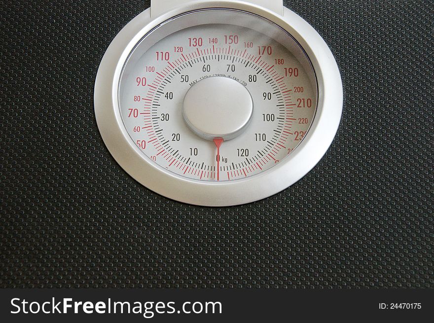 Close up view of analog black body weigh scale with silver top dial on wood background. Close up view of analog black body weigh scale with silver top dial on wood background