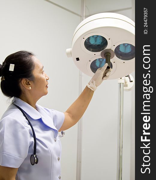 Nurse with surgical lamp in operation room