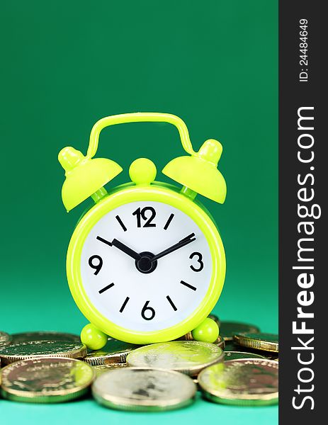 A yellow alarm clock placed on some golden coins, asking the question how long before your investment matures?. A yellow alarm clock placed on some golden coins, asking the question how long before your investment matures?