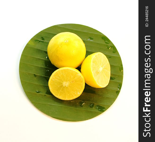 Fresh yellow lemons (half and full) on green banana leaf