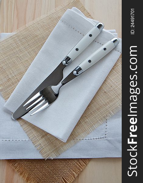 Knife and fork table setting on wood with white linen