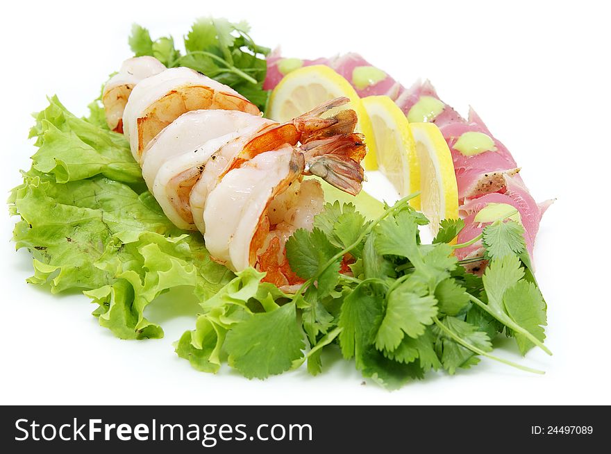 Shrimp and tuna with greens and sauce on a white background