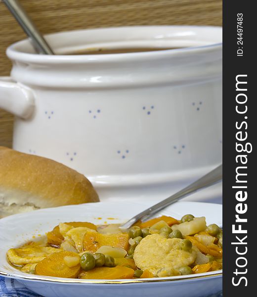 Vegetable soup with green peas,carrot,and pasta in a white plate-background bread and bowl (shallow dof). Vegetable soup with green peas,carrot,and pasta in a white plate-background bread and bowl (shallow dof)