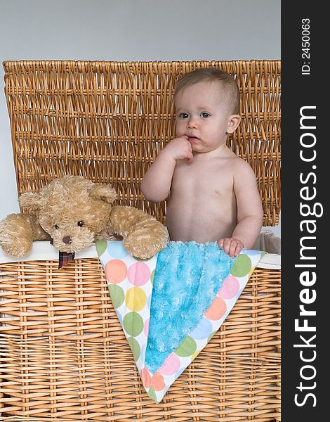 Image of cute baby and teddy bear peeking out of a wicker trunk