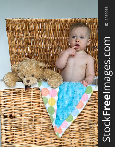 Image of cute baby and teddy bear peeking out of a wicker trunk