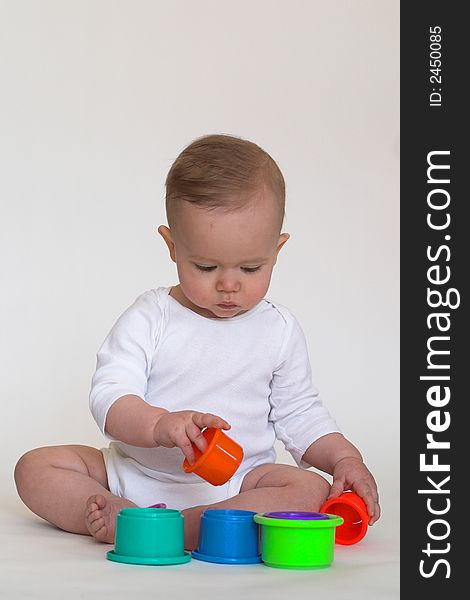 Image of an adorable baby playing with colorful stacking cups. Image of an adorable baby playing with colorful stacking cups