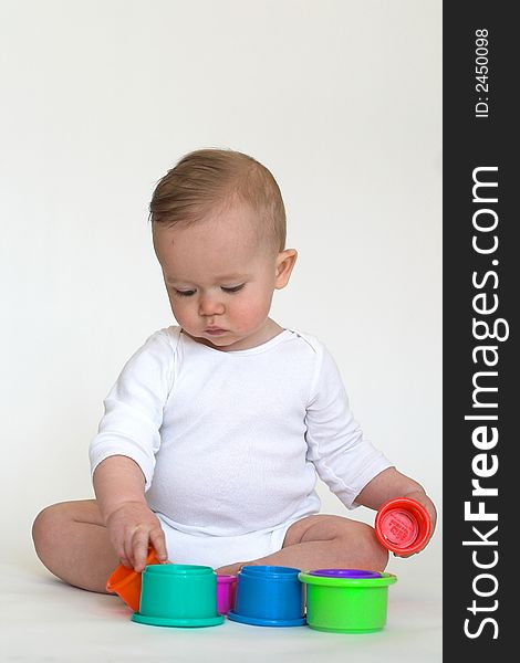 Image of an adorable baby playing with colorful stacking cups. Image of an adorable baby playing with colorful stacking cups