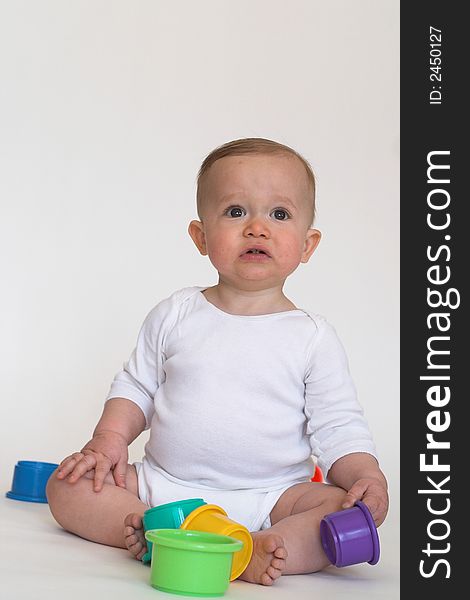 Image of an adorable baby playing with colorful stacking cups. Image of an adorable baby playing with colorful stacking cups