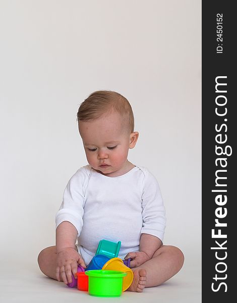 Image of an adorable baby playing with colorful stacking cups. Image of an adorable baby playing with colorful stacking cups