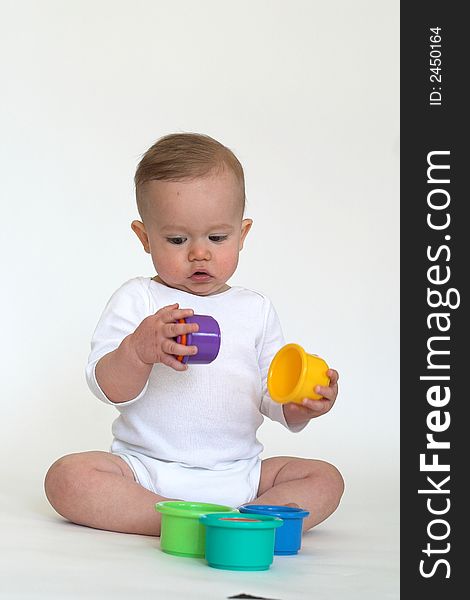 Image of an adorable baby playing with colorful stacking cups. Image of an adorable baby playing with colorful stacking cups