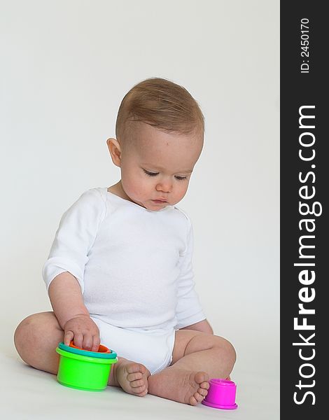 Image of an adorable baby playing with colorful stacking cups. Image of an adorable baby playing with colorful stacking cups