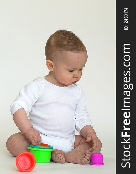 Image of an adorable baby playing with colorful stacking cups. Image of an adorable baby playing with colorful stacking cups