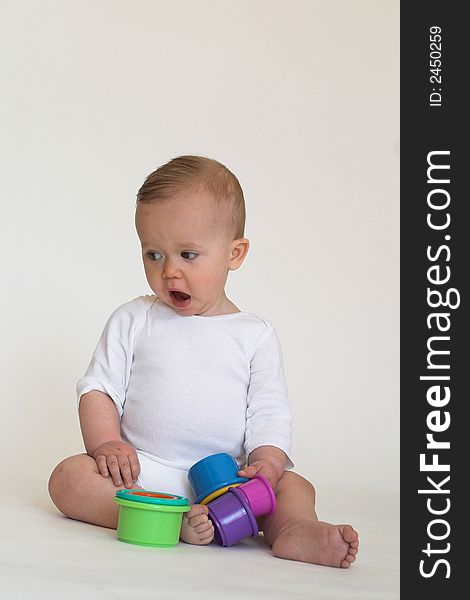 Image of an adorable baby playing with colorful stacking cups. Image of an adorable baby playing with colorful stacking cups