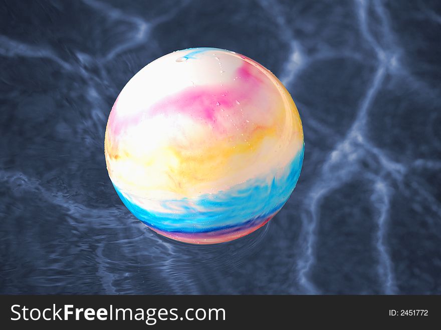 A colorful toy ball floating in a swimming pool. A colorful toy ball floating in a swimming pool