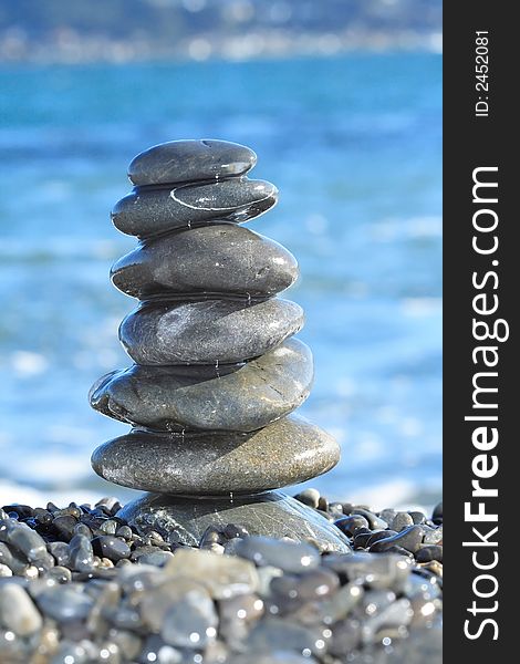 A stack of stones, balanced perfectly, set against a backdrop of a blue harbour. A stack of stones, balanced perfectly, set against a backdrop of a blue harbour