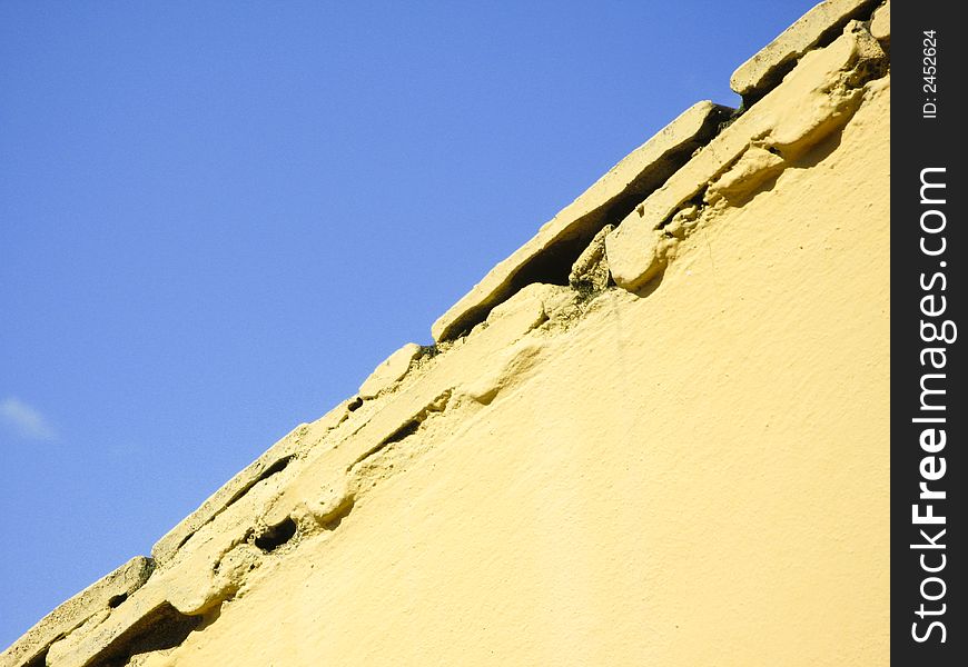 Part of fresh yellow wall and blue sky