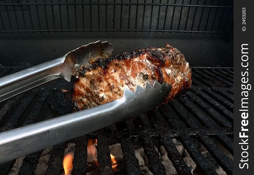 Photo of a marinated pork loin being cooked on a smoker grill. Photo of a marinated pork loin being cooked on a smoker grill