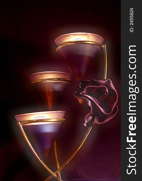 A tower of 3 candles glowing with a silken rose. A tower of 3 candles glowing with a silken rose.