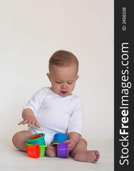 Image of an adorable baby playing with colorful stacking cups. Image of an adorable baby playing with colorful stacking cups