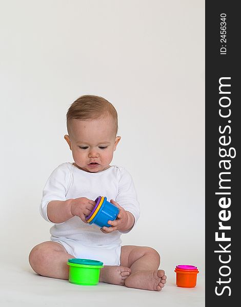 Image of an adorable baby playing with colorful stacking cups. Image of an adorable baby playing with colorful stacking cups