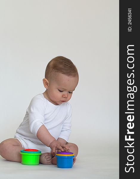 Image of an adorable baby playing with colorful stacking cups. Image of an adorable baby playing with colorful stacking cups